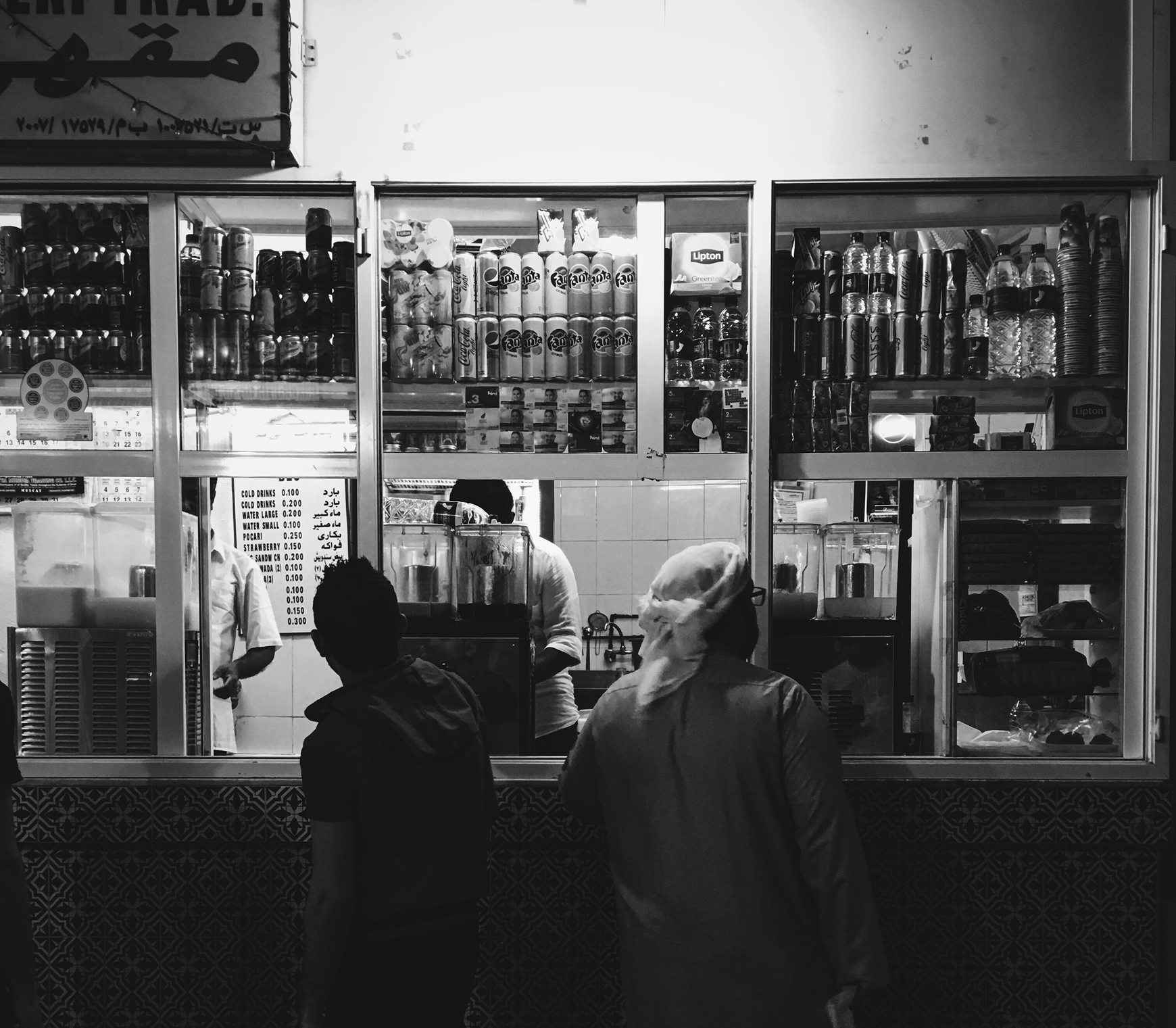 Historický pohľad na malý obchod s dochucovadlami a potravinami v tubách, s ľuďmi stojacimi pri okienku obchodu